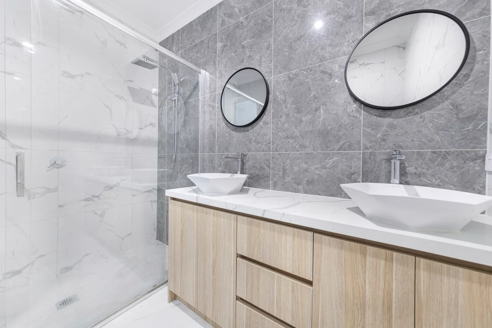 Modern bathroom with marble tile, double vanity and glass shower