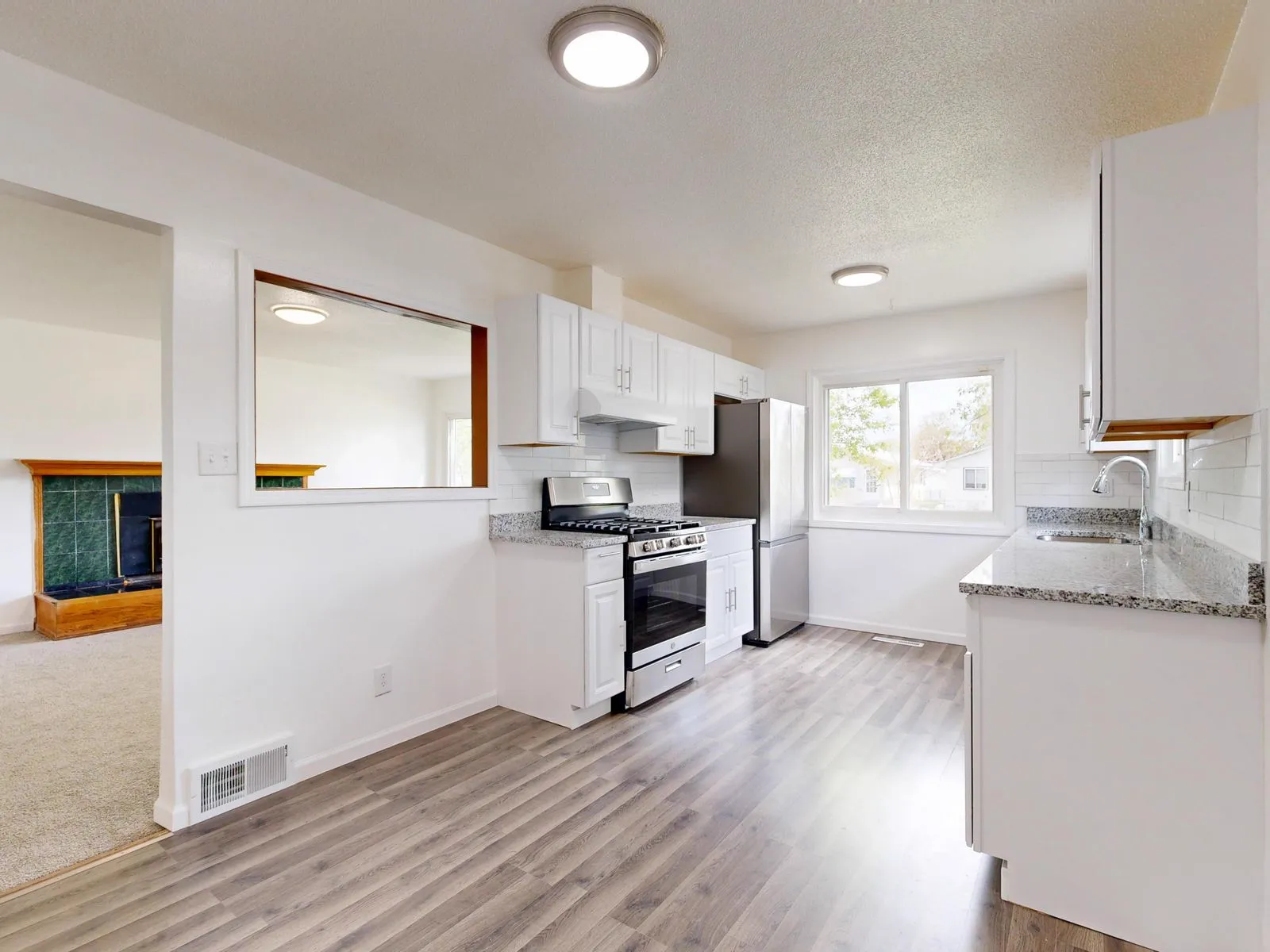 Renovated kitchen with white cabinets, granite counters and hardwood floors