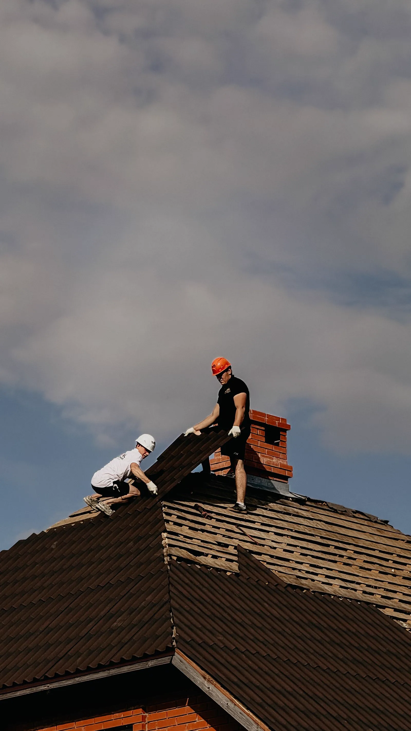 Two workers installing shingles on a roof