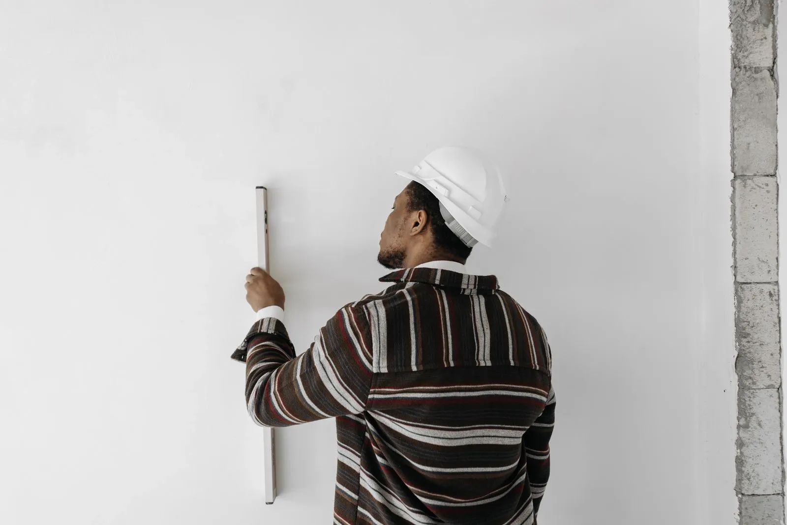 Contractor checking a freshly finished interior wall with a straightedge